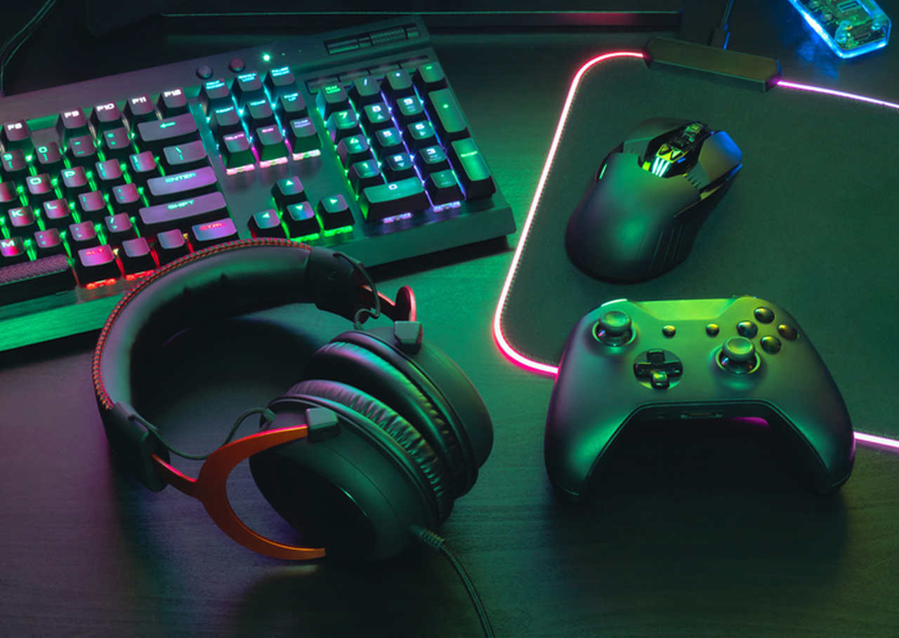 Periféricos gamers sobre uma mesa: teclado, mouse, headset e controle