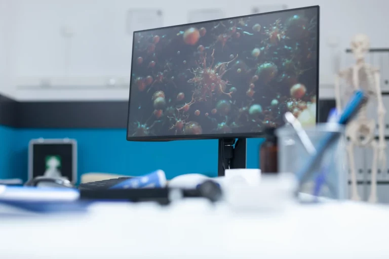Monitor de computador exibindo imagem microscópica de vírus em consultório médico
