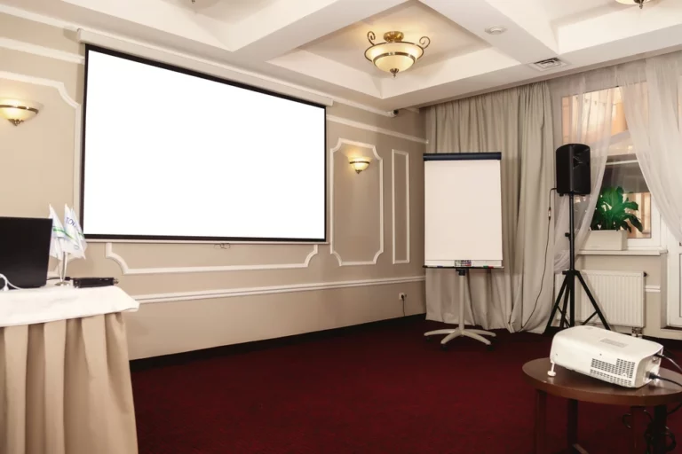 Sala de conferências com uma tela de projeção em branco na parede.
